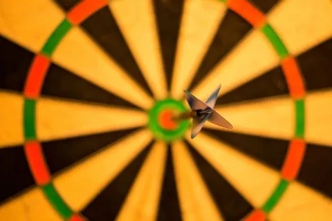 Anak panah dart menancap di lingkaran tengah papan dart